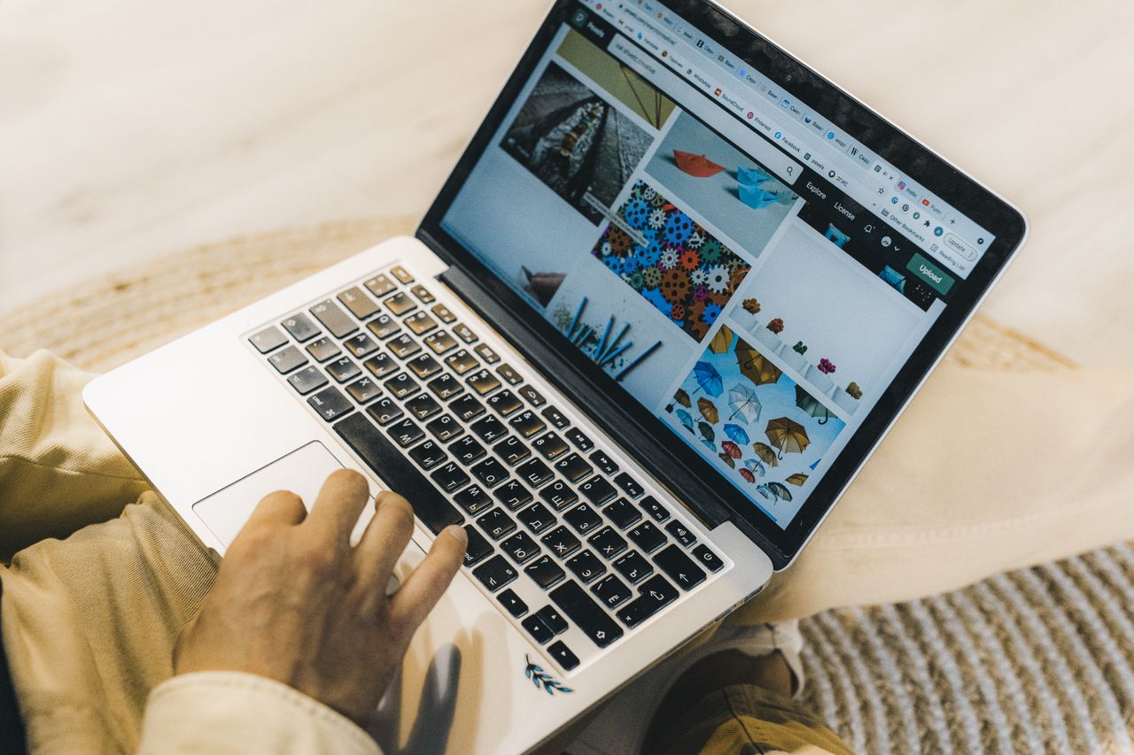 who-we-are A person using a laptop to browse stock photo websites. Freelancing work in a cozy setting.